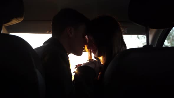 Portrait of Young Pretty Lovers Looking at Each Other with Tenderness and Sitting in Car