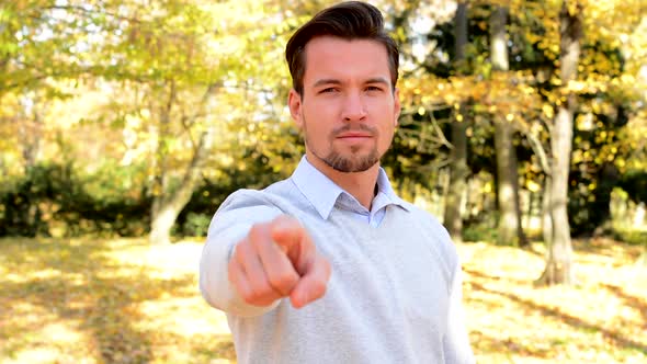 Young Man Stands in the Woods and Emphatically Shows Forefinger Ahead.