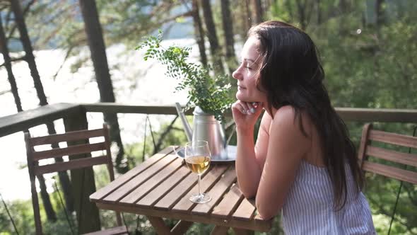 Attractive Brunette with a Glass in Her Hands Enjoying Nature in the Mountains, Sitting on the