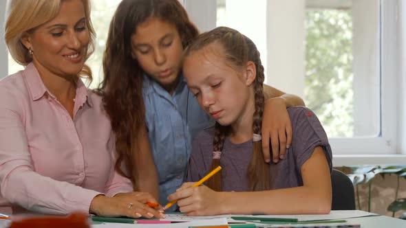 Cute Young Girl Joining Her Classmate and Art Teacher in Working on a Project