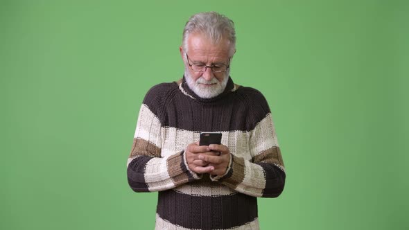 Handsome Senior Bearded Man Wearing Warm Clothing Against Green Background