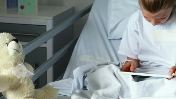 Sick girl using digital tablet on bed