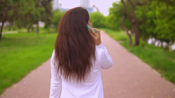 Joyful Female Has Phone Conversation Outdoors