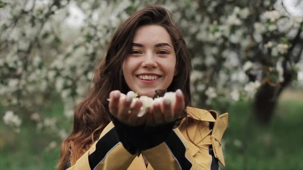 A Gentle Young Snare Girl Holds Flower Petals in Her Palms and Blows Them Straight To the Camera