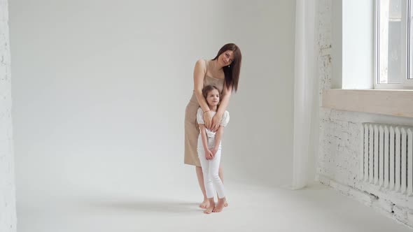 Mom and Daughter Pose in a White Photo Studio for a Photo Shoot