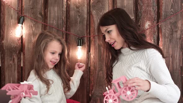 Young Mother and Her Daughter Happily Playing with Toys on Christmas Eve