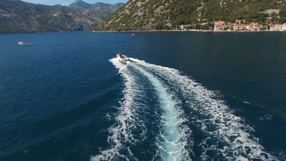Motor Boat Sails Along the Bay of Kotor Against the Backdrop of Green Mountains