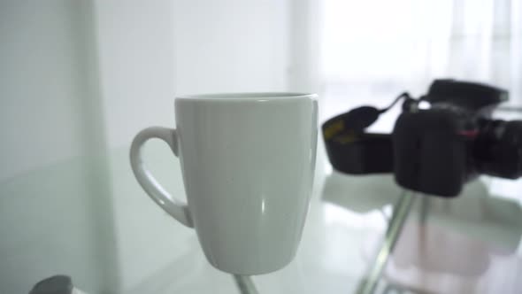 A cup of coffee and a camera on the table, waiting for the person who goes for them