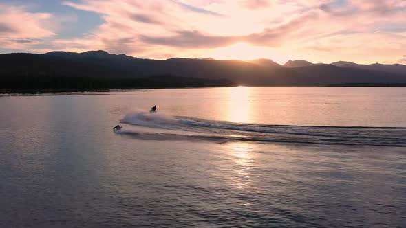 Colorful sunset over lake following a watercraft pulling person on boogie board