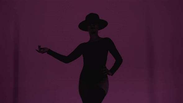 Silhouette of Woman in Hat Bodysuit and Stockings Walking Forward to Camera Under Flashing Violet