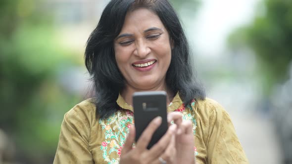 Mature Happy Beautiful Indian Woman Using Phone in the Streets Outdoors
