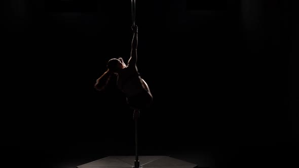 Dancer in Underwear Spinning on a Pole . Black Background. Silhouette