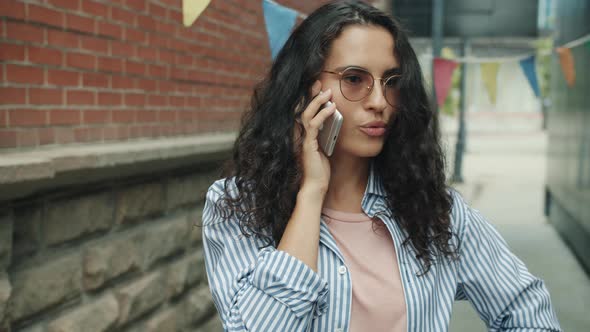 Emotional Young Asian Woman Speaking on Mobile Phone and Gesturing Standing Alone Outside