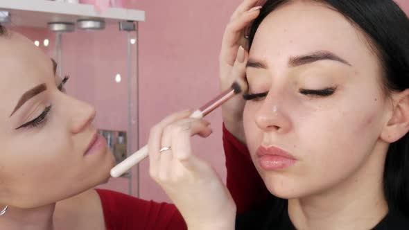Girl Stylist Makeup Artist Applies Foundation Under the Foundation with a Special Brush on the Face