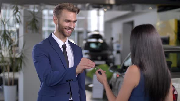 Smiling Auto Dealer Giving Car Key To Female Buyer