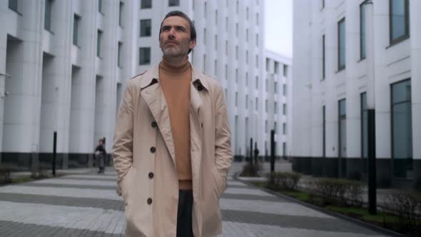 Portrait of an adult successful businessman looking around. Serious business man standing outdoors.