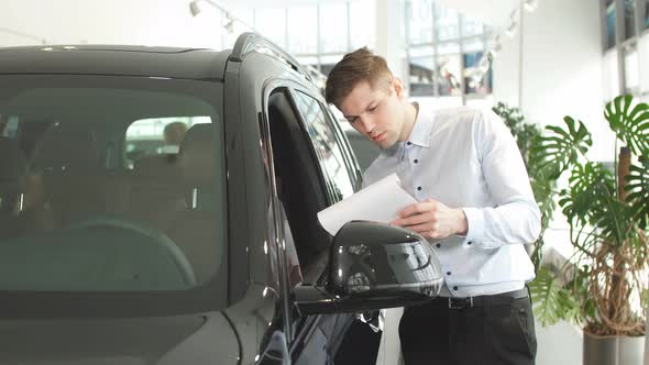 Young Caucasian Guy Examining New Car Before Making Purchase.