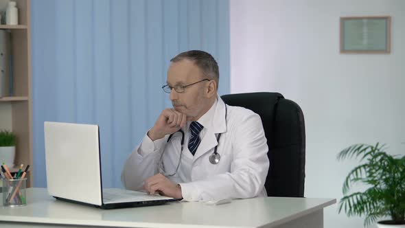 Head Physician Carefully Studying Medical Records of Patients at Clinic Office