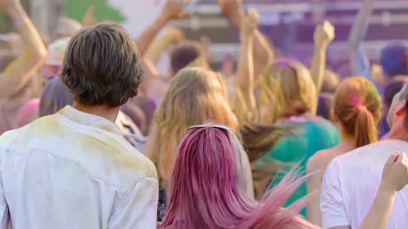 Crowd of Young People Covered in Colored Paint Dancing at Open Air Music Fest