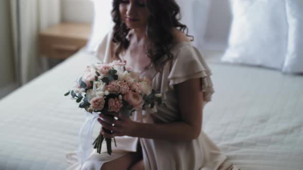 A Girl Sits on a Bed with a Large Bouquet of Flowers