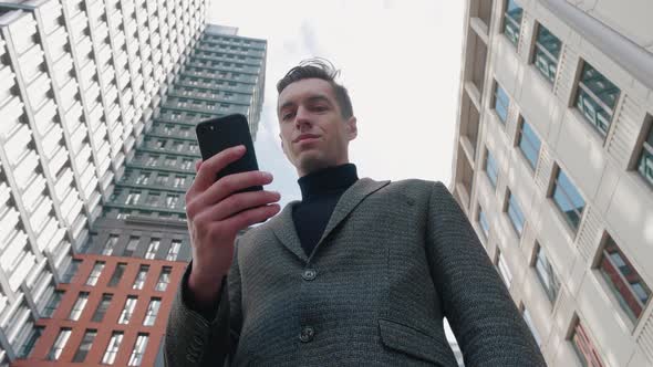 Man Using Business App on Smartphone on City Background. Handsome Young Businessman Communicating on