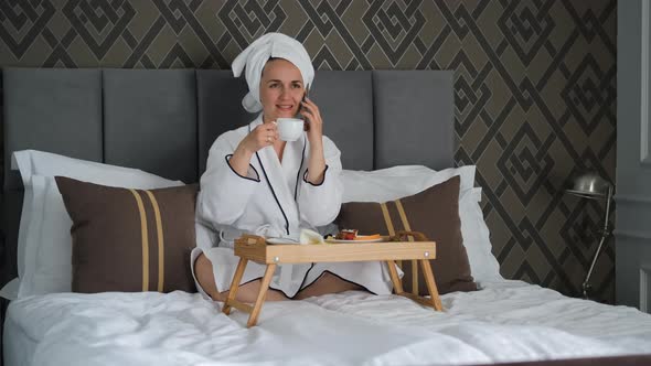 Woman in Bathrobe Calling on Phone at Hotel Room