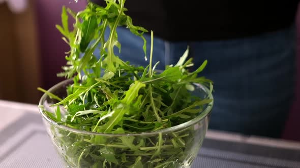 Healthy Lifestyle  Woman Pouring Arugula Into Glass Bowl