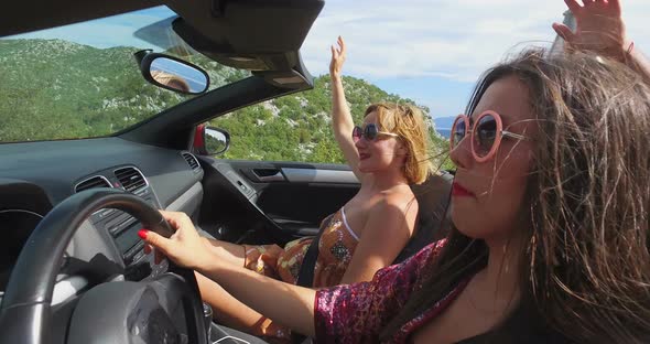 Attractive woman with round frame pink sunglasses driving friends in convertible