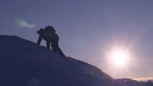 Climber Climbs Snowy Mountain in Rays of Bright Sun Tourist Makes Climb To Top on Background