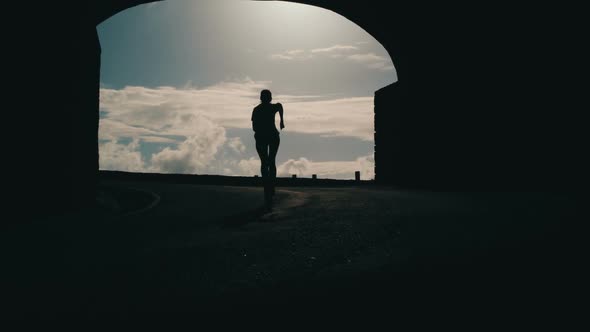 Tracking Shot of a Woman Silhouette Running Out From Tunnel Towards the Sunlight. Burst of Bright