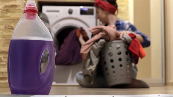 Young woman unloads laundry from washing machine into laundry basket after washing. Housework