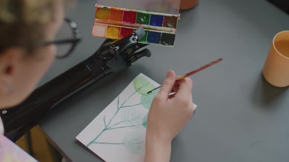 Woman with Prosthetic Arm Painting Picture with Watercolor Paints