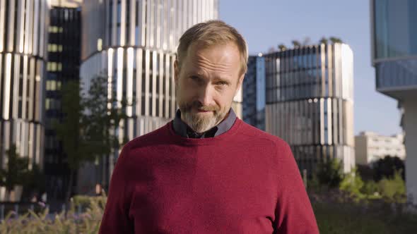 A Middleaged Handsome Caucasian Man Points at the Camera and Says Something in an Urban Area