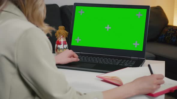 Business woman at home working on a laptop with green screen chroma key display.