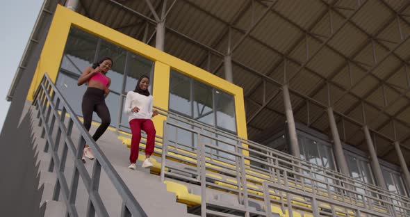 Two Black Girlfriends Going Down the Stadium Stairs