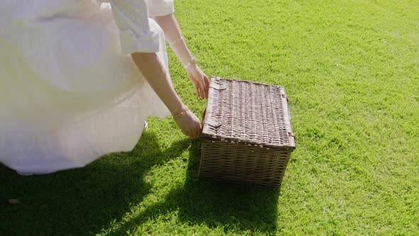 Woman in White Romantic Dress Having Lunch with Food and Wine in Picnic Basket