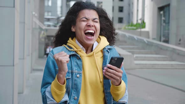 Happy African American Woman Looking in Smartphone Feel Surprised Saying WOW and Makes Yes Gesture