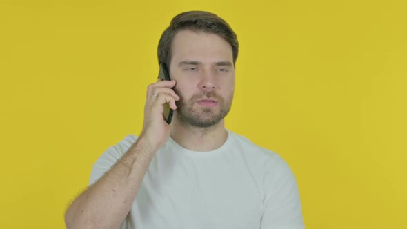 Young Man Talking on Phone on Yellow Background
