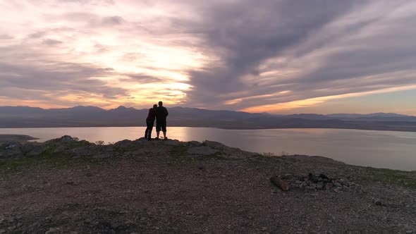 Couple standing on mountain top watching the sunset