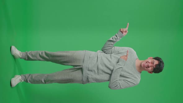 Full Body Of Asian Man With A Smile Pointing To The Side While Standing In The Green Screen