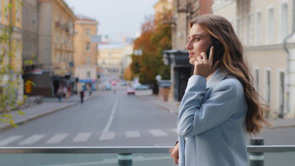 Serious Young Successful Lady Business Woman Girl in Blue Suit Stands on Balcony Talking Mobile
