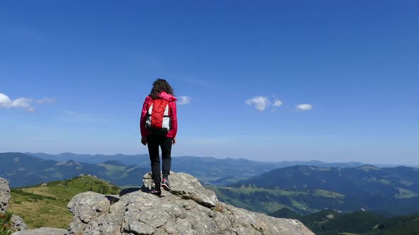 Girl on Top of the Mountain with a Backpack. Rejoice at Achievement