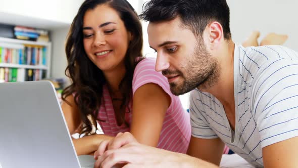 Couple interacting with each other while using laptop on bed