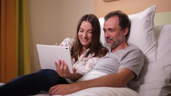 Joyful Husband and Wife Watching Video in Hospital