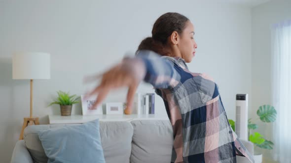 Active woman Latino listen to music and dance on floor in living room.