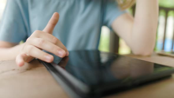 Teenage Girl Sits At Wooden Table In a Summer Cafe In Headphones With Phone