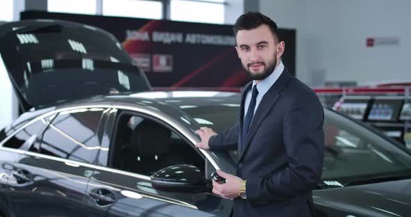 Successful Caucasian Brunette Man with Brown Eyes Standing Next To New Car with Keys and Smiling