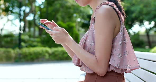 Woman use of mobile phone online in the park