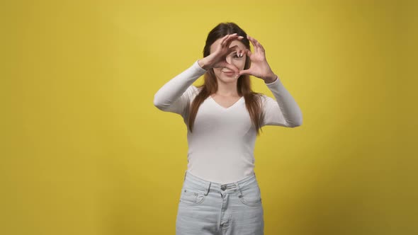 Attractive Girl in a White Sweater Shows the Heart Symbol with Her Hands