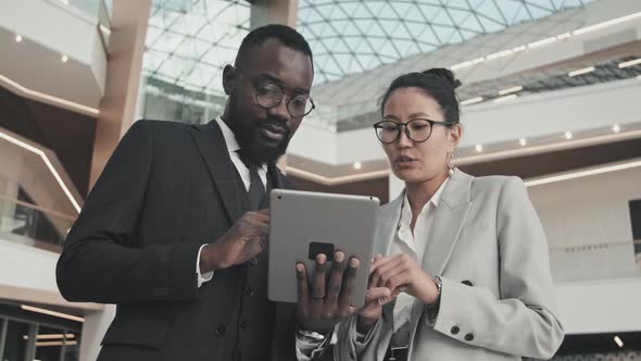 Cheerful Businesspeople Using Tablet in Office Building